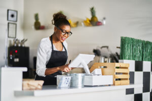 Smiling,shop,assistant,using,pos,point,of,sale,terminal,to