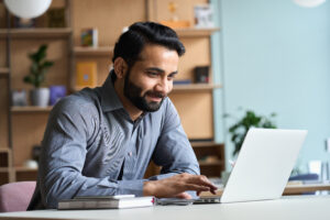 Smiling,indian,business,man,working,on,laptop,at,home,office.
