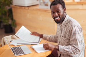 Cheerful,man,posing,while,working,with,documents,in,cafe
